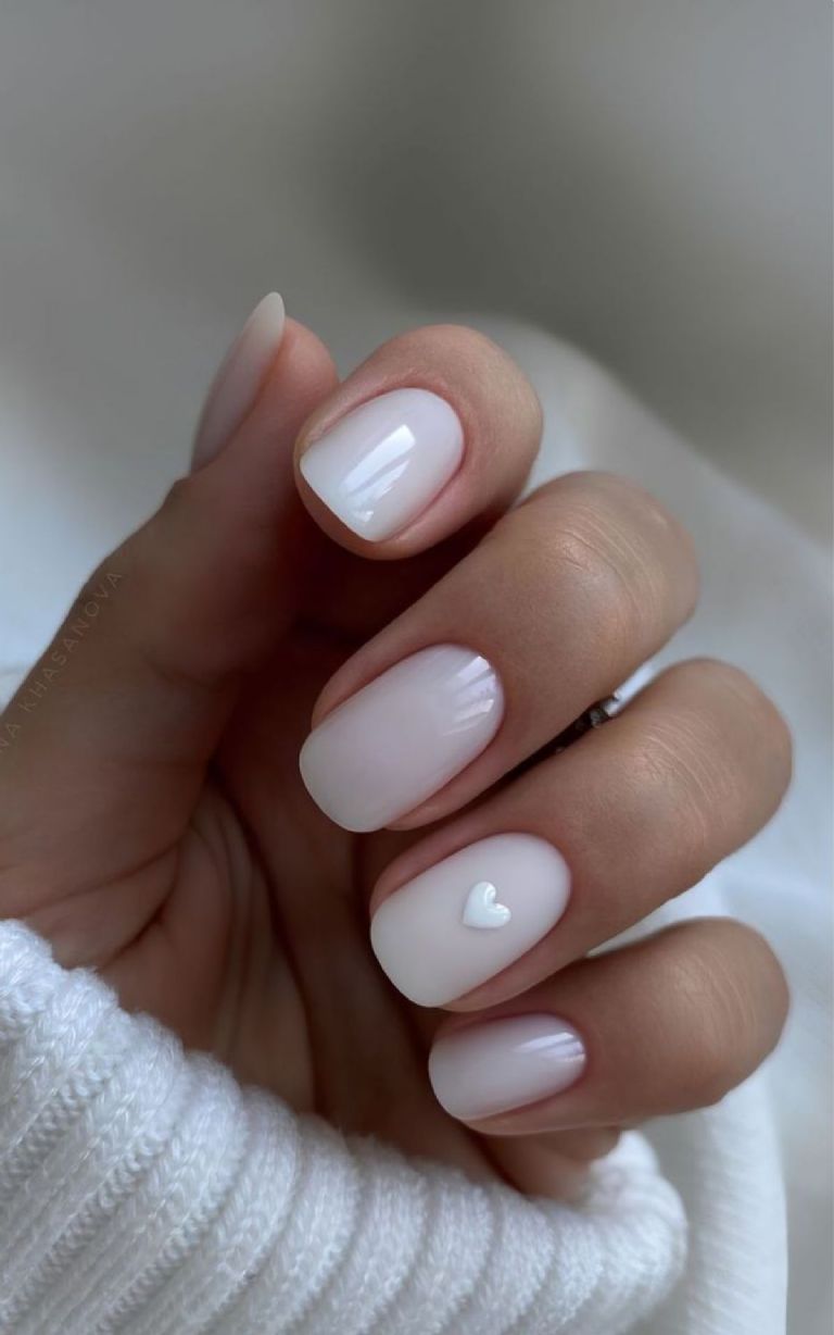 Diseño de uñas blancas milky con corazón minimalista