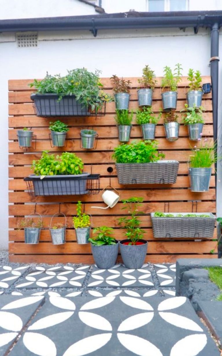 Jardín con muro verde hecho con pallets y macetas